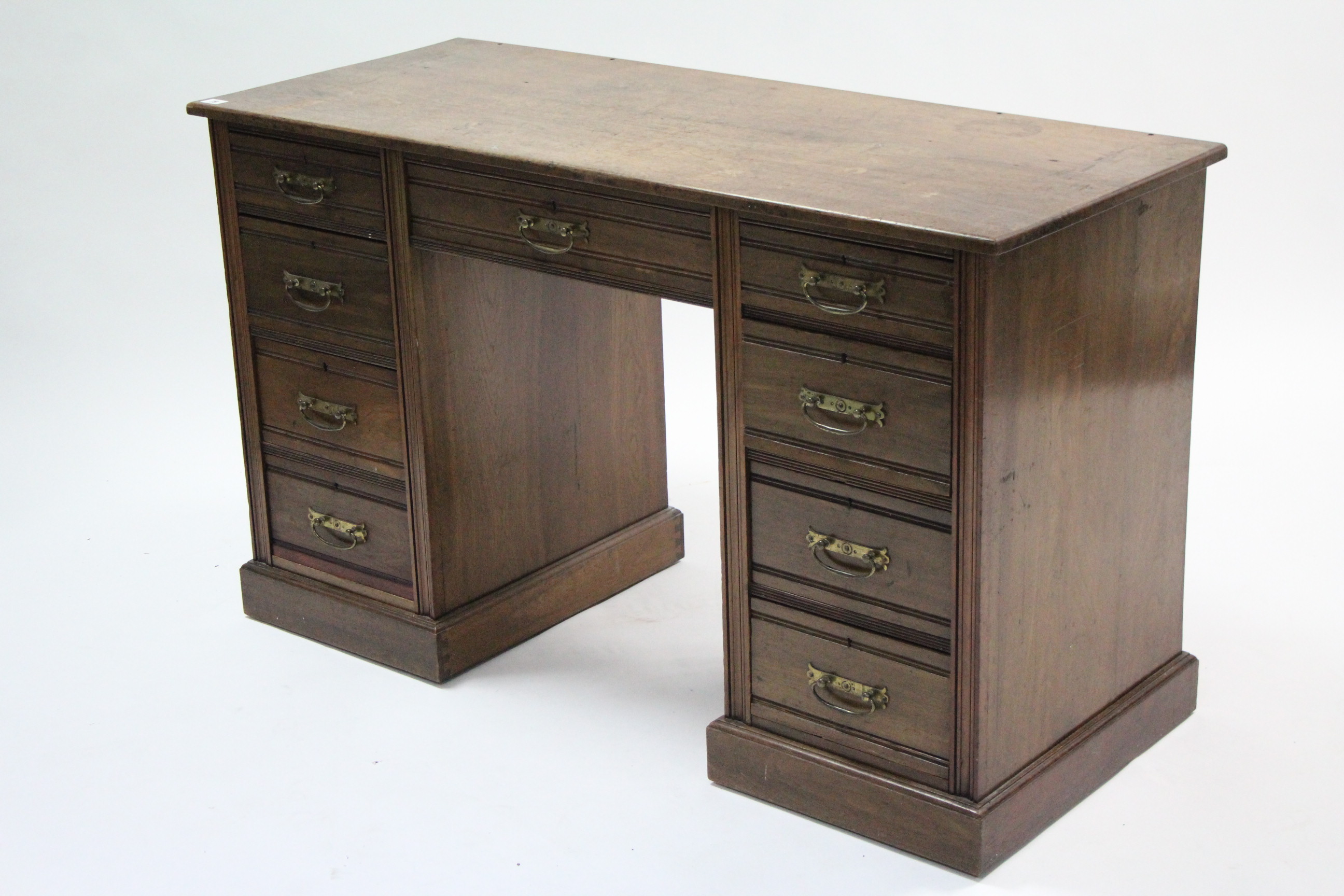 A late Victorian walnut knee-hole desk fitted with an arrangement of nine drawers, & on plinth base,