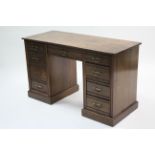 A late Victorian walnut knee-hole desk fitted with an arrangement of nine drawers, & on plinth base,