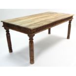 A teak dining table with rectangular top, carved frieze & on turned legs, 72” x 36”.