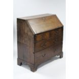 A late 18th century oak bureau with fitted interior enclosed by a sloping fall front above two short