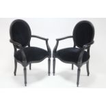 A pair of 19th century continental-style ebonised frame elbow chairs with padded oval backs & sprung