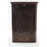 A Georgian figured mahogany hanging corner cupboard, fitted three shelves enclosed by panel door