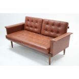 A 1960’s TEAK-FRAME TWO-SEATER SETTEE with loose cushions to the seat & back, upholstered buttoned