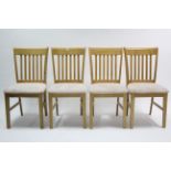A set of four maple-finish rail-back dining chairs with padded seats, & on square tapered legs.