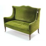 A late 19th/early 20th century two-seater settee with shaped back & sprung seat upholstered green