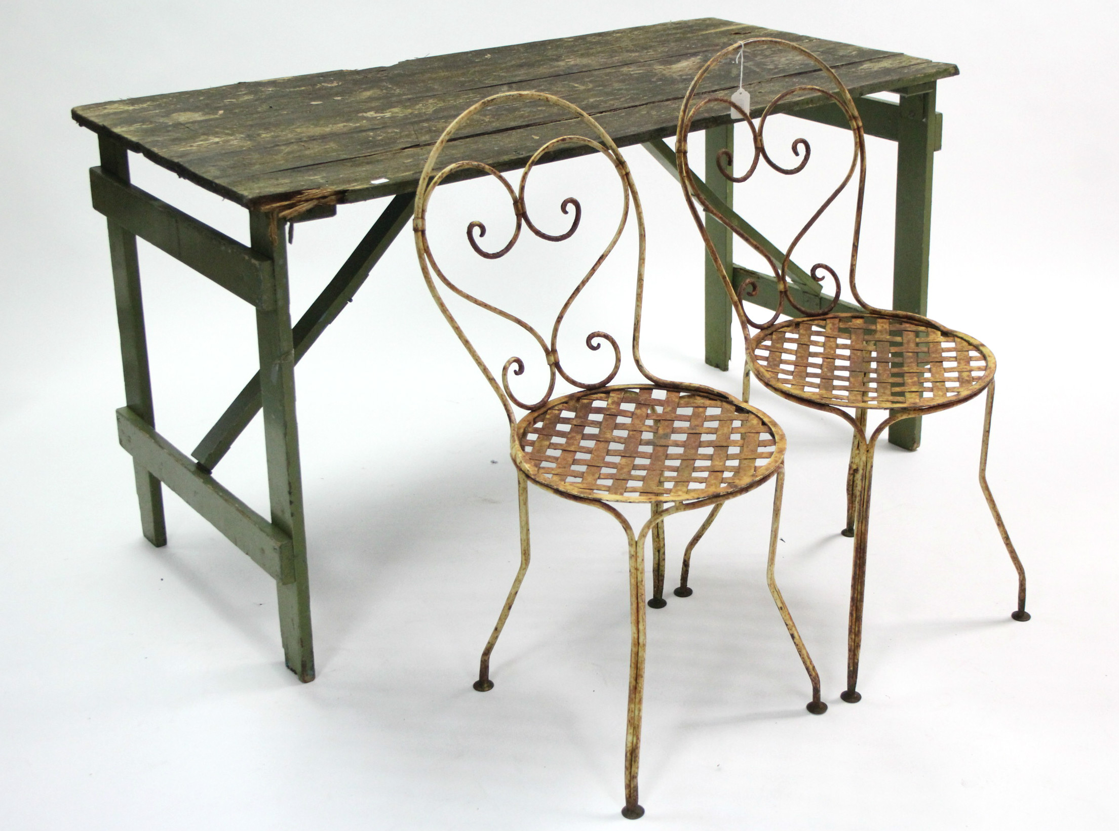 A pair of white painted wrought-iron patio chairs; & a green painted wooden trestle table, 53¾” long