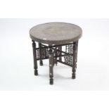 An eastern brass engraved tray-top occasional table, on folding carved wooden stand, 24” diameter.