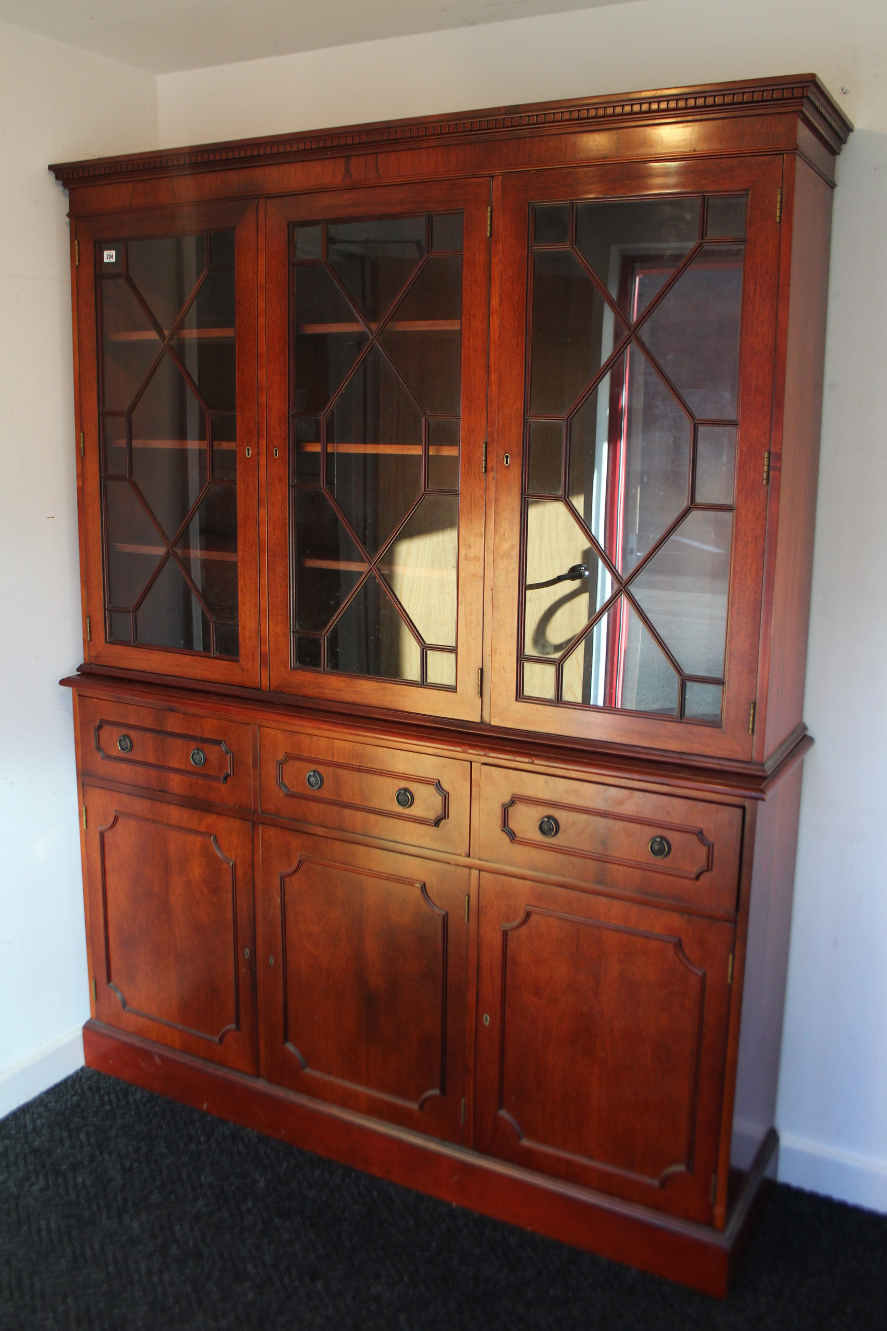 A mahogany tall standing cabinet, the upper part fitted nine shelves enclosed by three glazed doors,