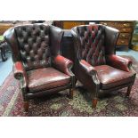 A pair of buttoned deep red (dark) leather & brass-studded wing-back armchairs, on short turned