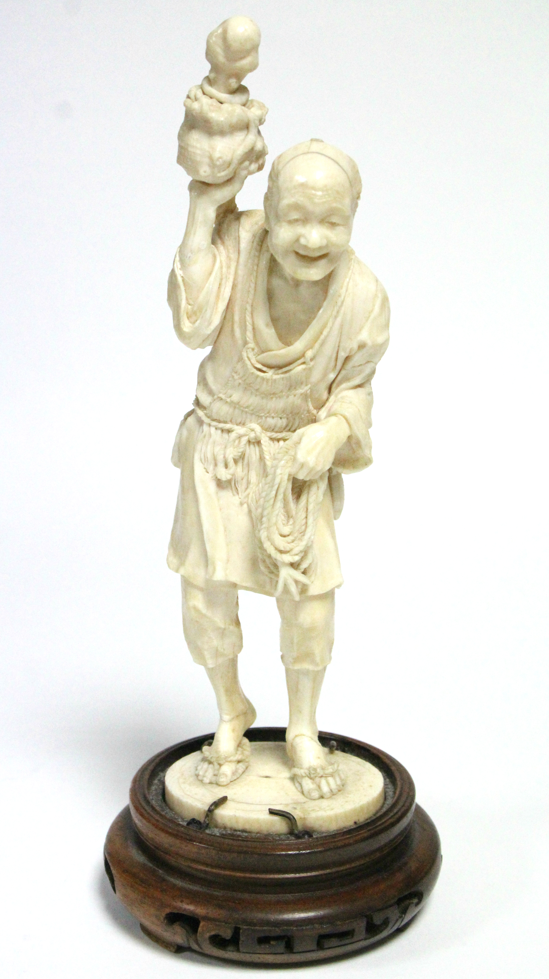 A LATE 19th century JAPANESE IVORY OKIMONO of a standing fisherman holding aloft an octopus in a pot