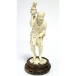 A LATE 19th century JAPANESE IVORY OKIMONO of a standing fisherman holding aloft an octopus in a pot