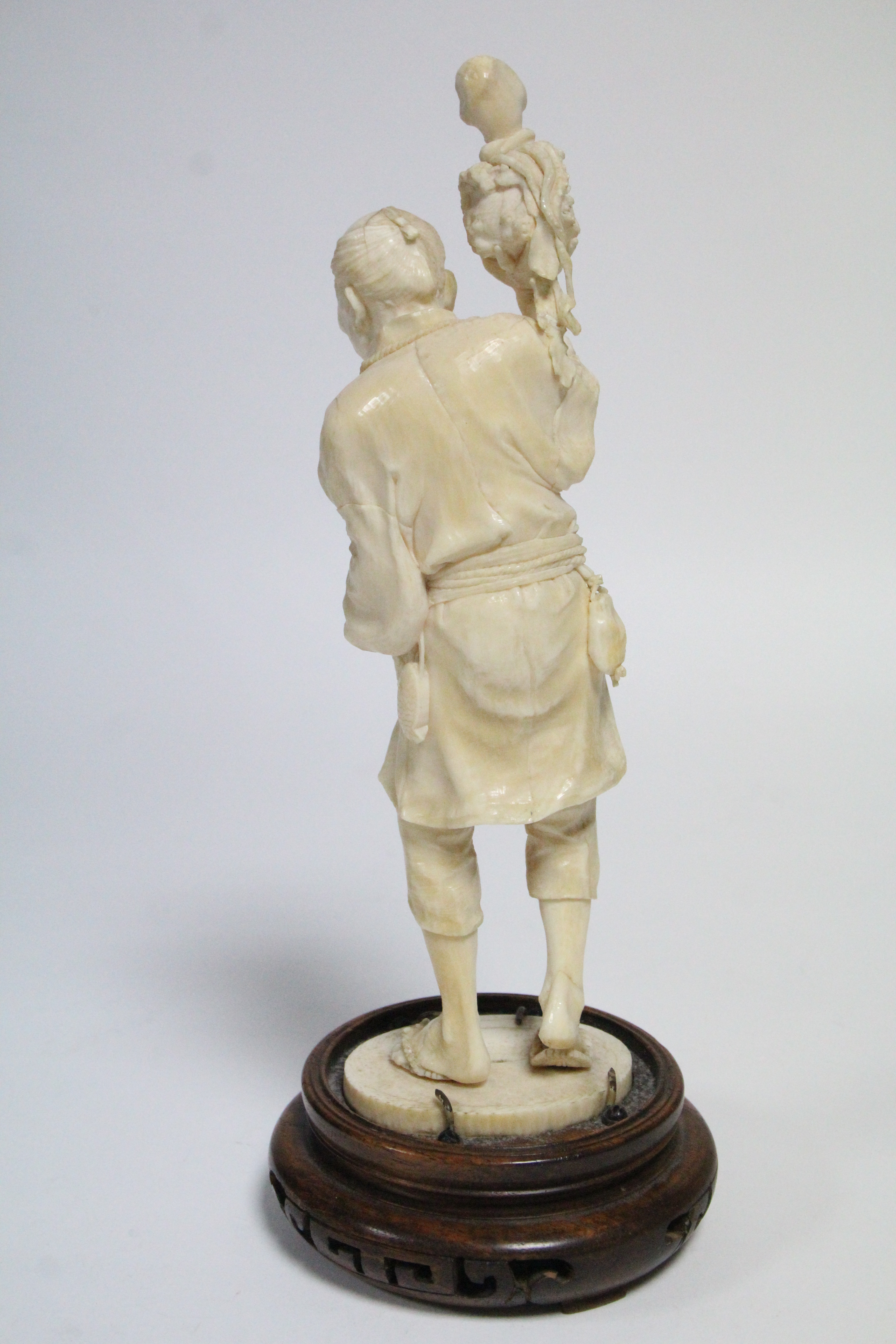 A LATE 19th century JAPANESE IVORY OKIMONO of a standing fisherman holding aloft an octopus in a pot - Image 3 of 6