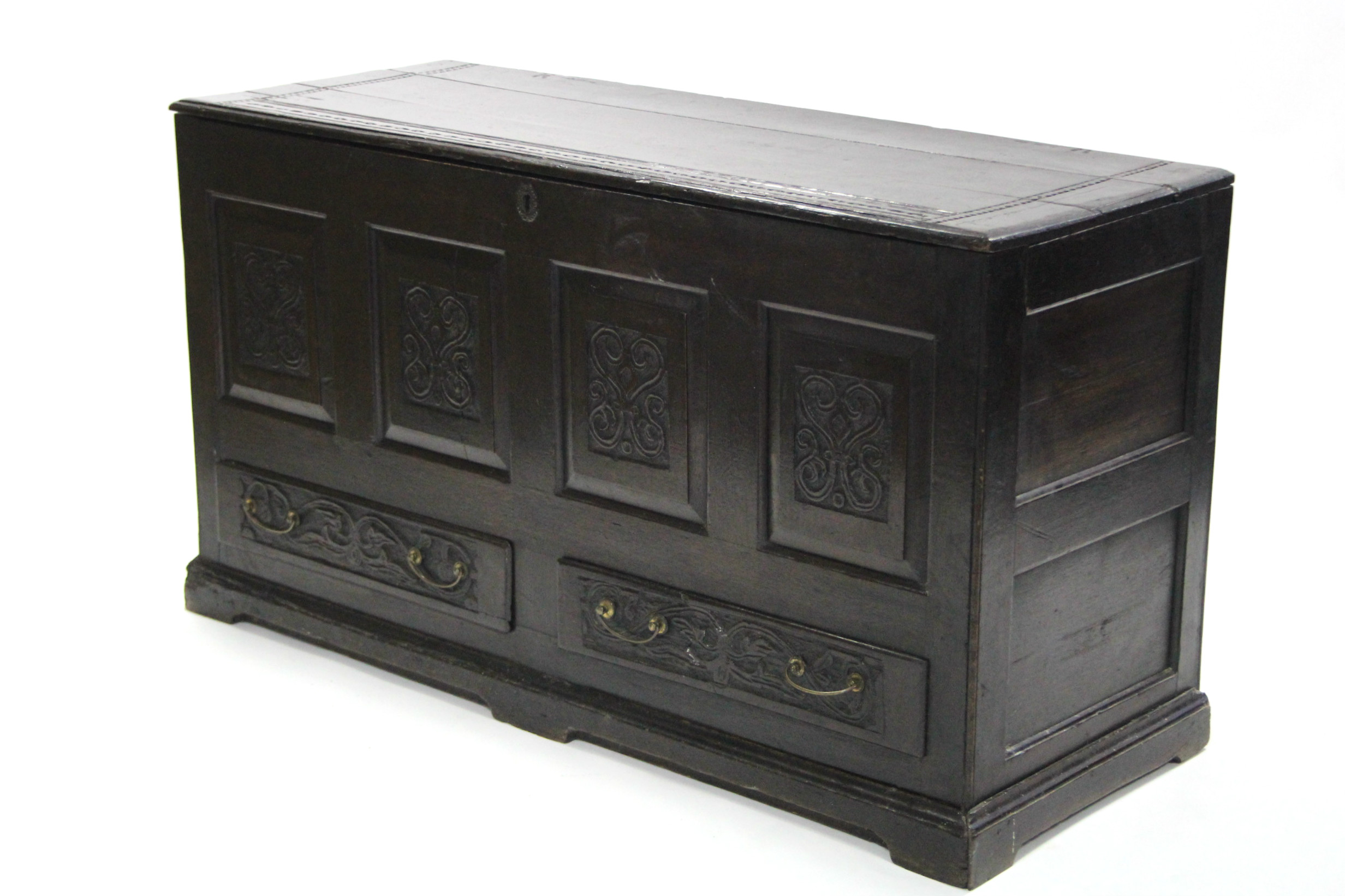 A late 17th century oak coffer with hinged lift-lid, having four carved panels to the front above