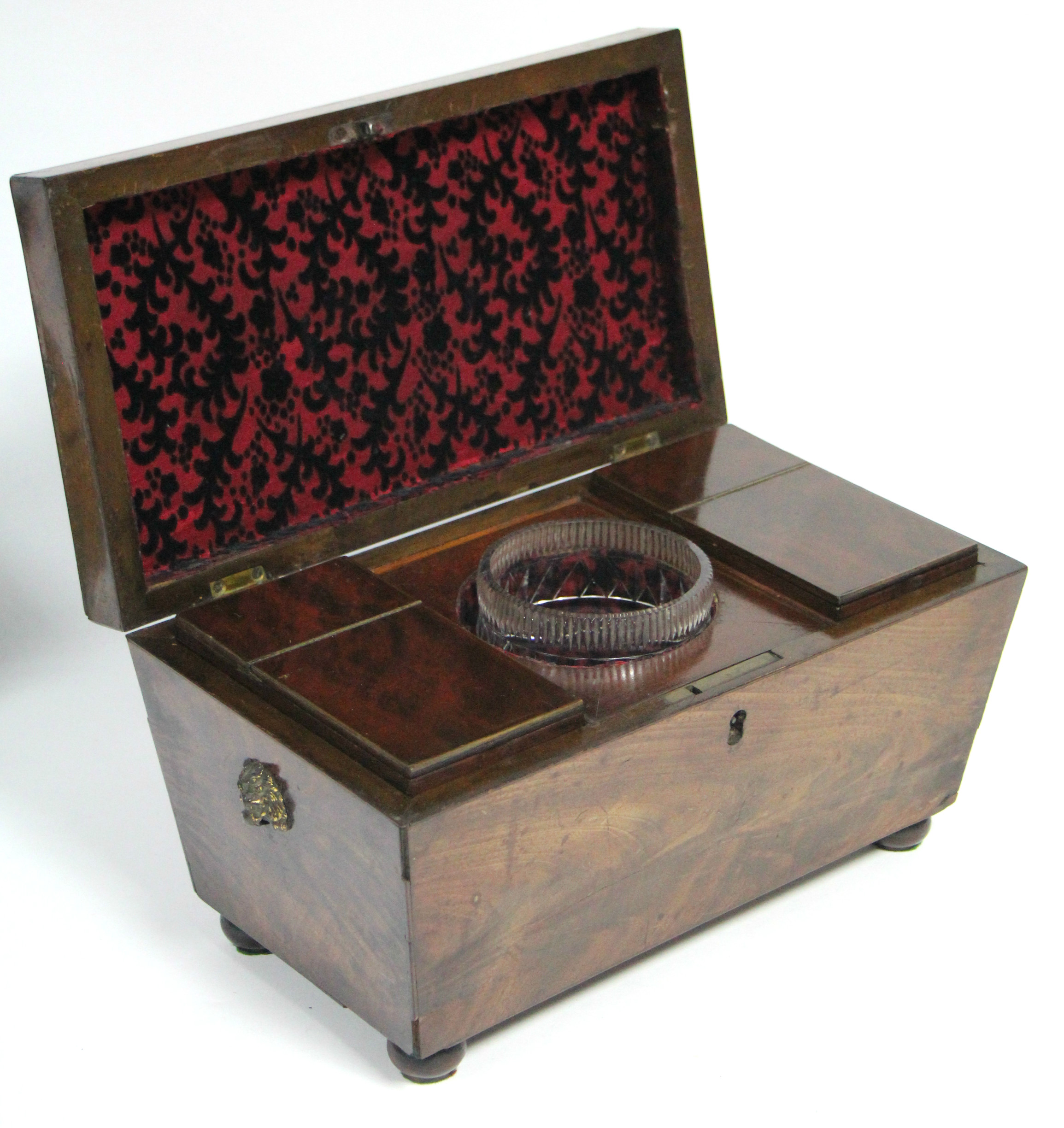 A regency figured mahogany rectangular tea caddy with tapered sides, brass lion-mask & ring side