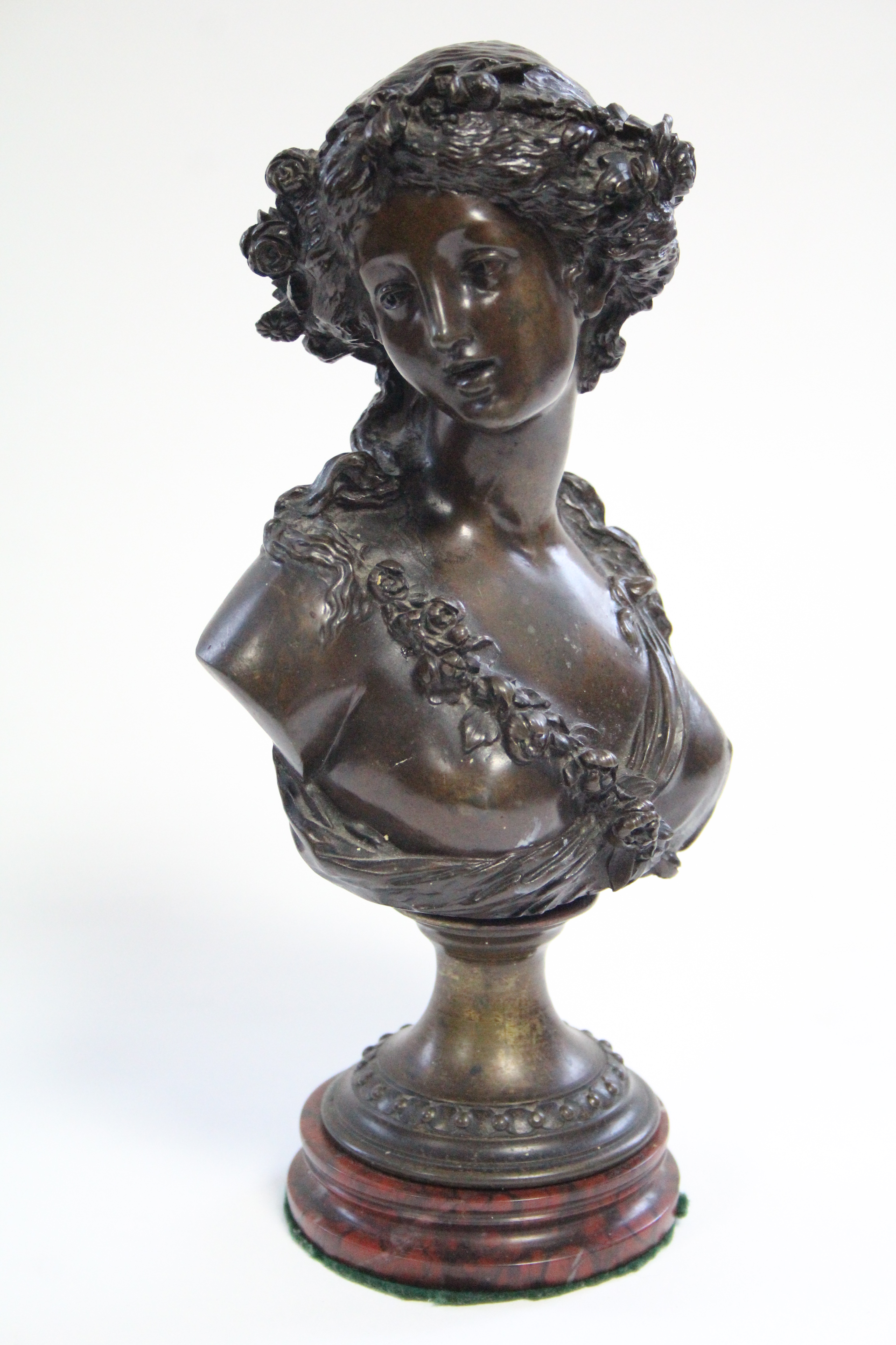 A 19th century bronze bust of a young woman with floral garland in her hair, on round socle &