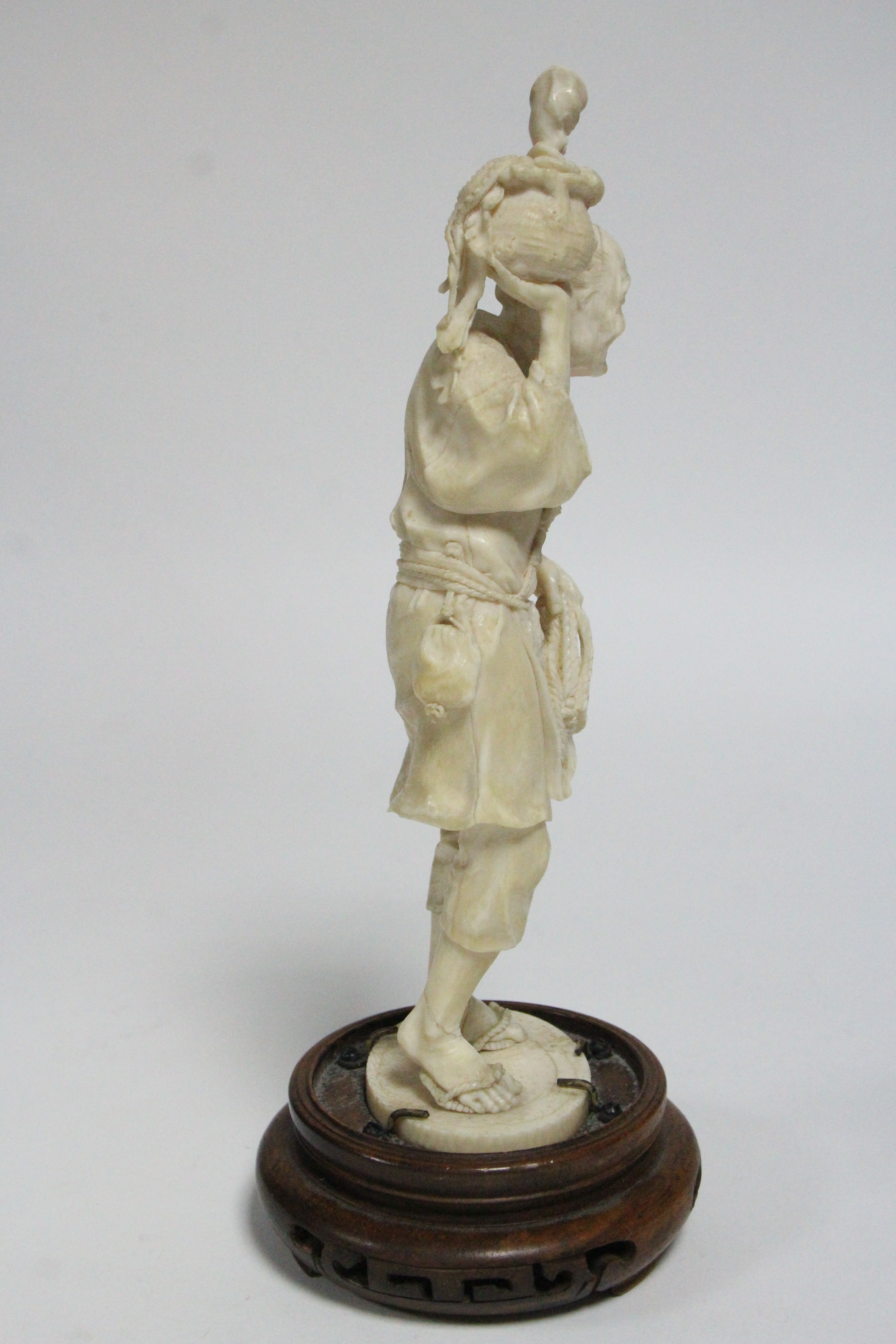 A LATE 19th century JAPANESE IVORY OKIMONO of a standing fisherman holding aloft an octopus in a pot - Image 4 of 6