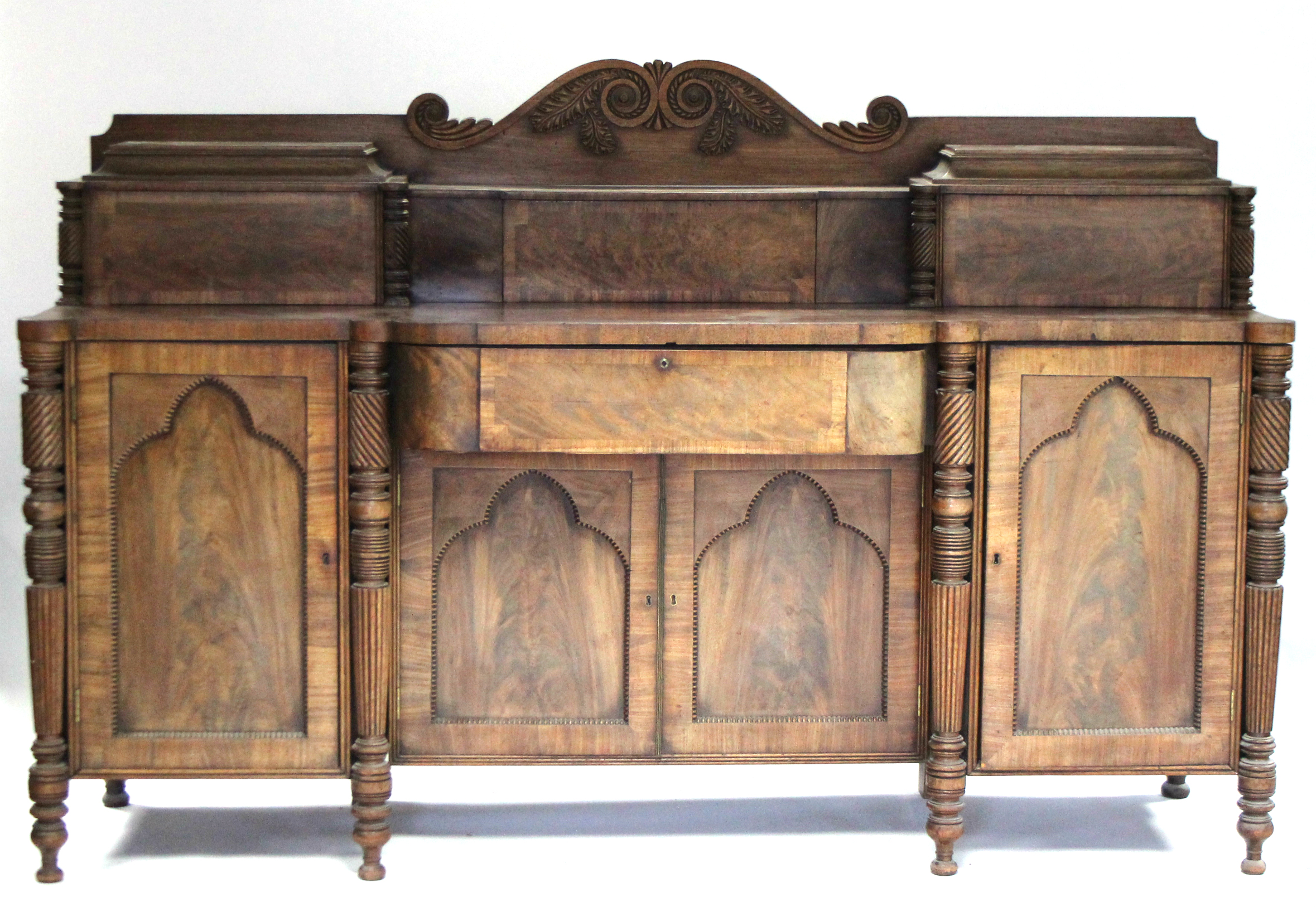 A Regency mahogany pedestal sideboard, the stage-back with carved scroll decoration to centre, the