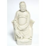 An 18th century Chinese blanc-de-chine figure of a dignitary dressed in long robes & seated in a