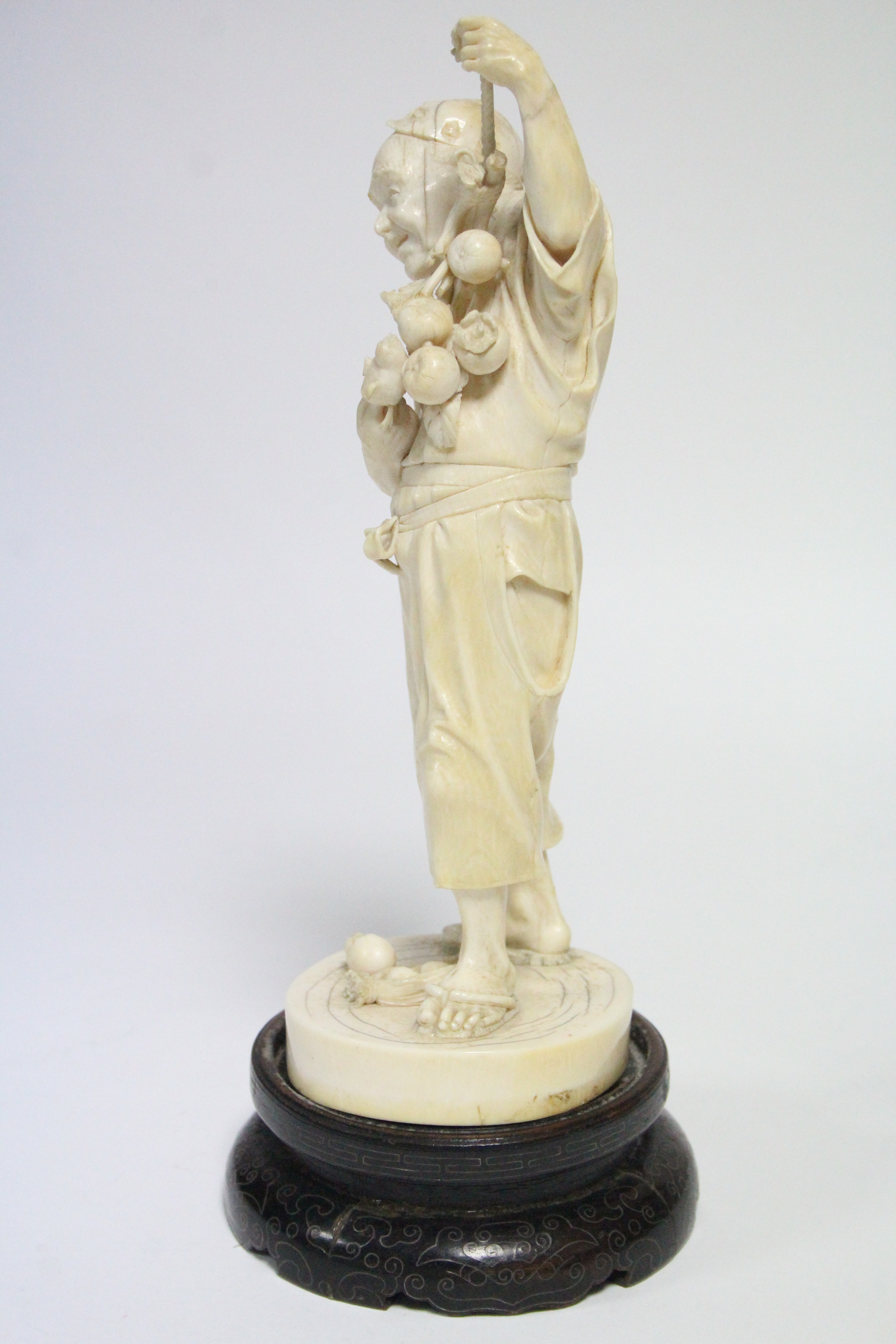 A LATE 19th century JAPANESE IVORY OKIMONO of a standing male farmer holding aloft a fruit-laden - Image 4 of 7