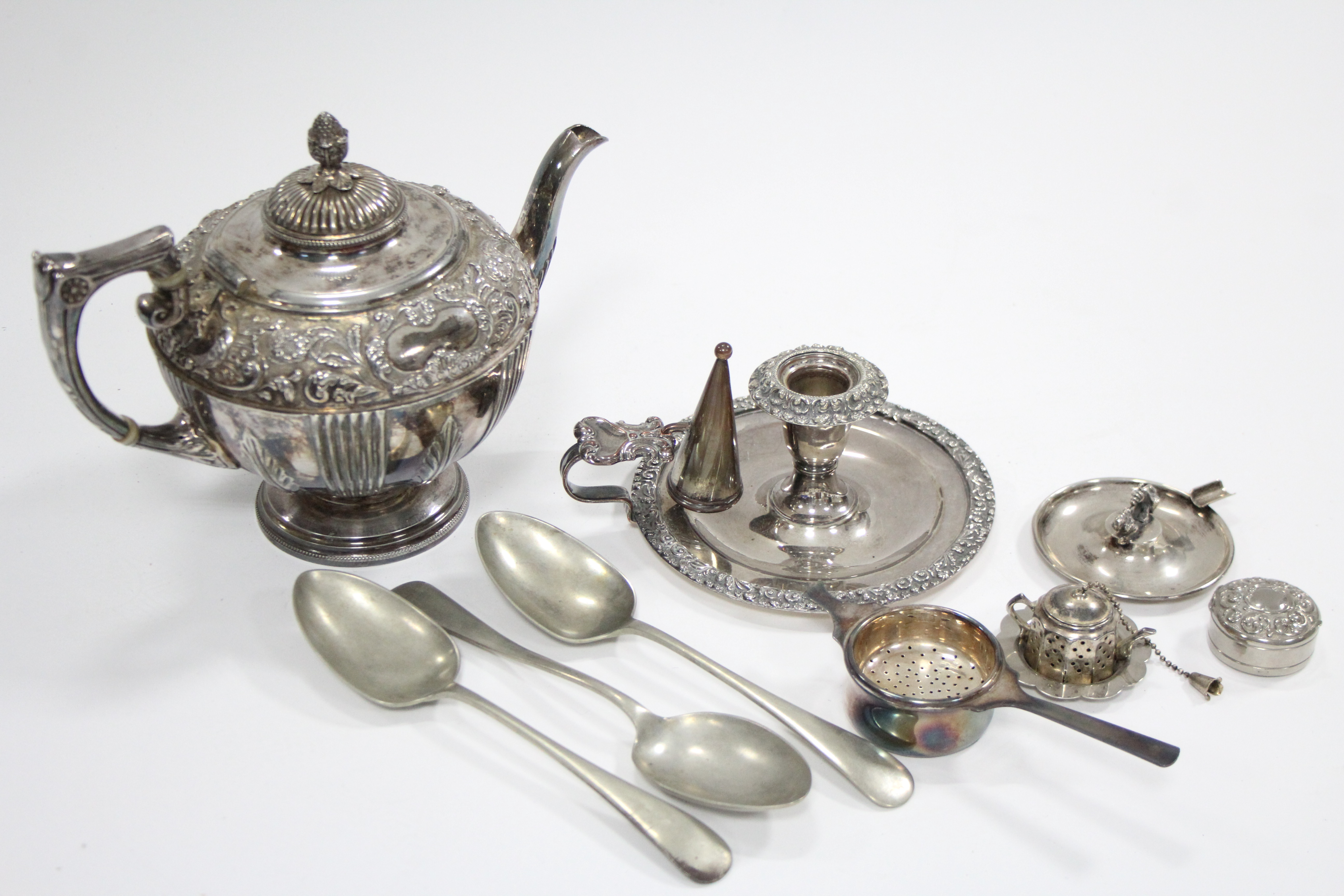 A circular embossed teapot; a chamber candlestick; an ashtray; various spoons, etc.