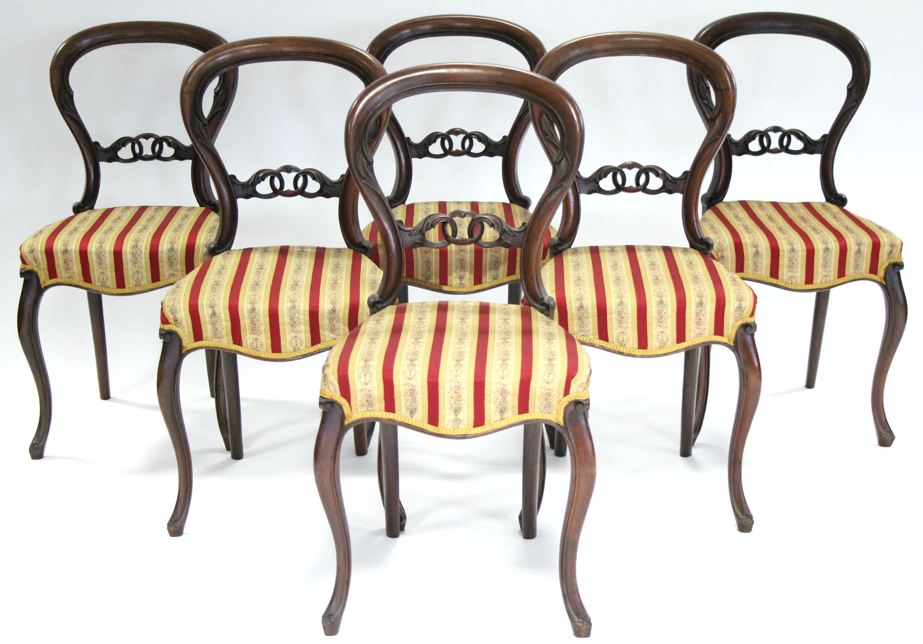 A set of six Victorian carved rosewood dining chairs with pierced centre rails to the balloon backs,