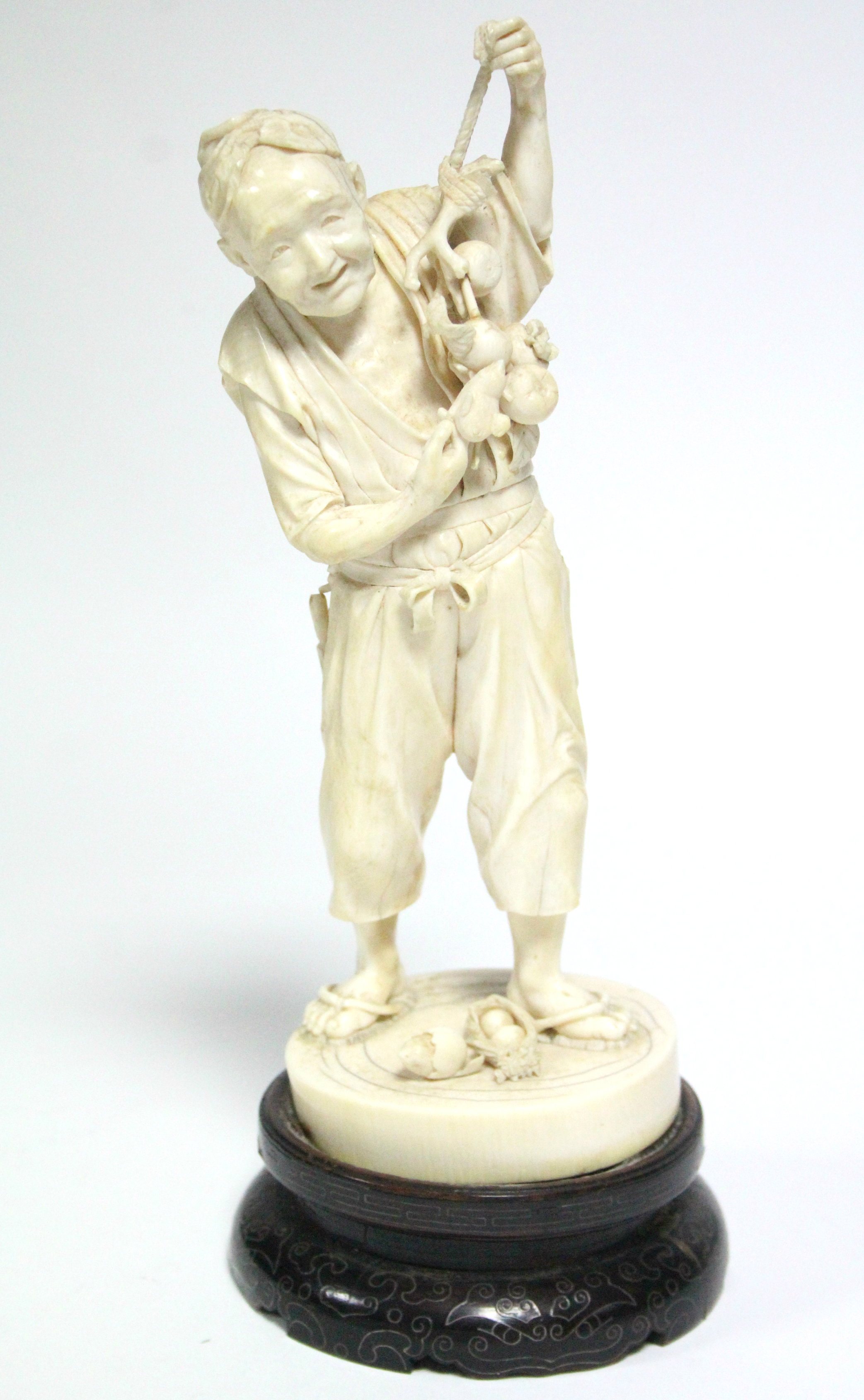 A LATE 19th century JAPANESE IVORY OKIMONO of a standing male farmer holding aloft a fruit-laden