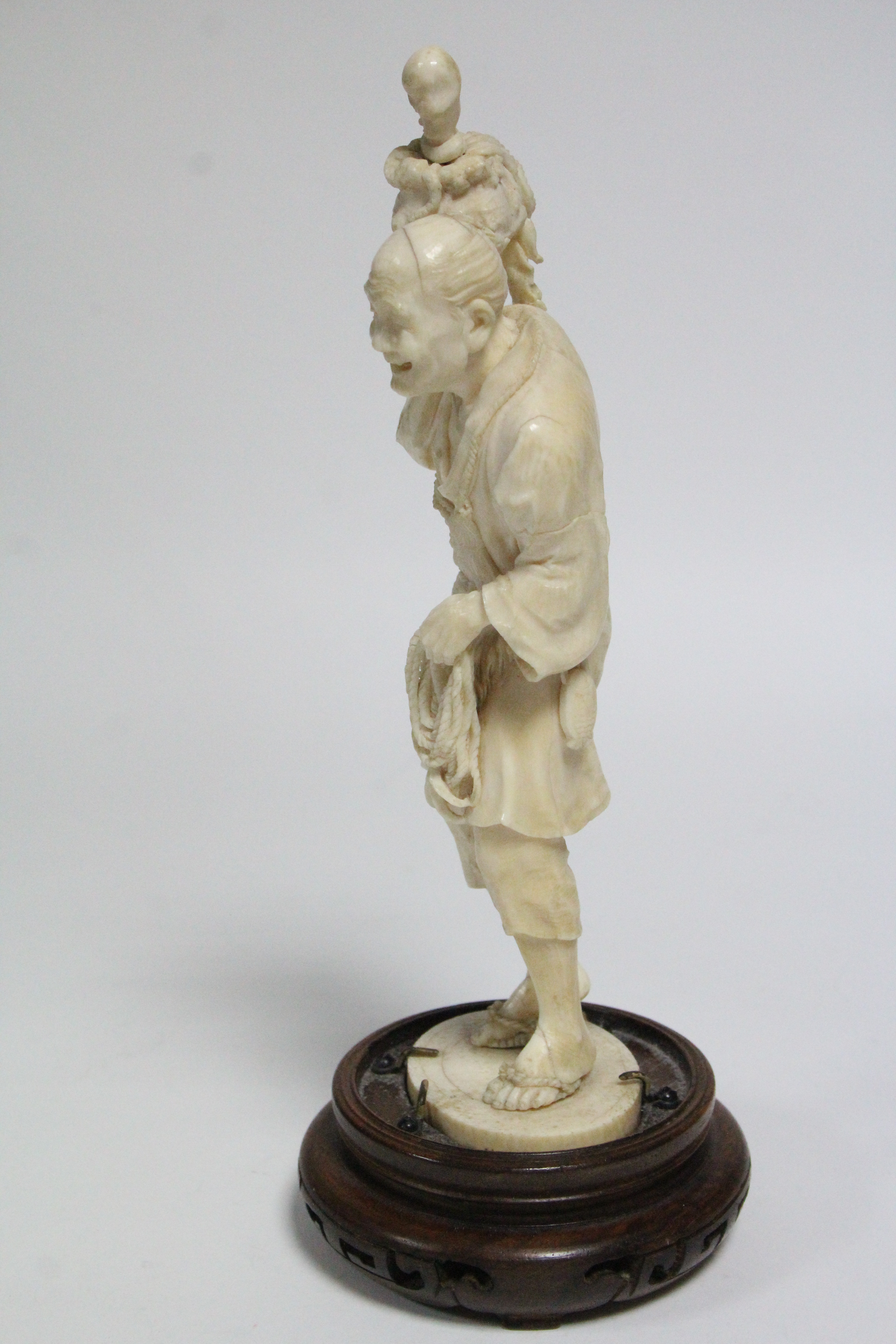 A LATE 19th century JAPANESE IVORY OKIMONO of a standing fisherman holding aloft an octopus in a pot - Image 2 of 6