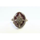 A 9ct. gold ring set oval cabochon garnet centred by a star motif set seed pearls.