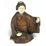 A late 19th century Japanese wood okimono of a kneeling Geisha, with ivory head & hands, signed on a