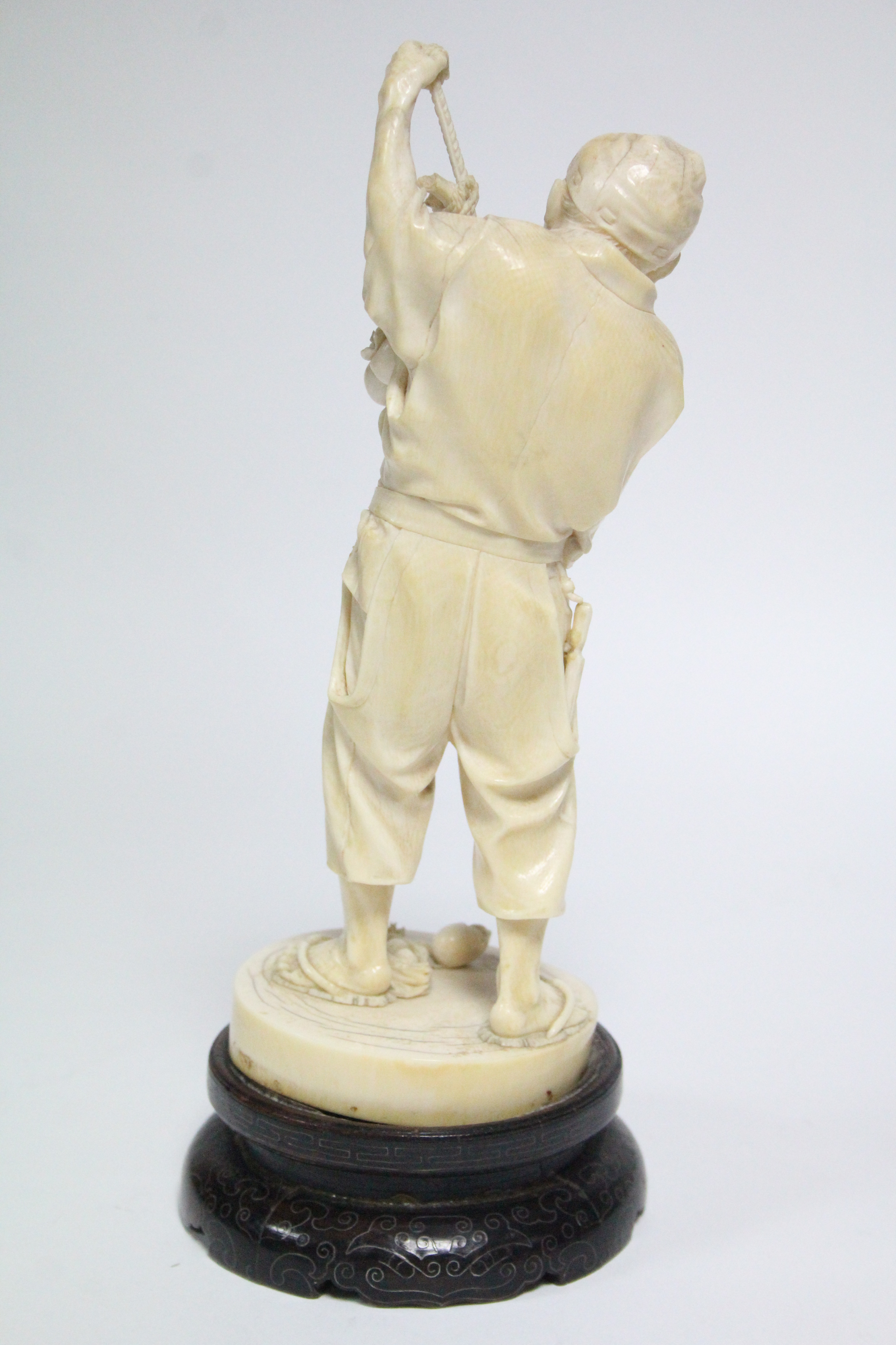 A LATE 19th century JAPANESE IVORY OKIMONO of a standing male farmer holding aloft a fruit-laden - Image 3 of 7