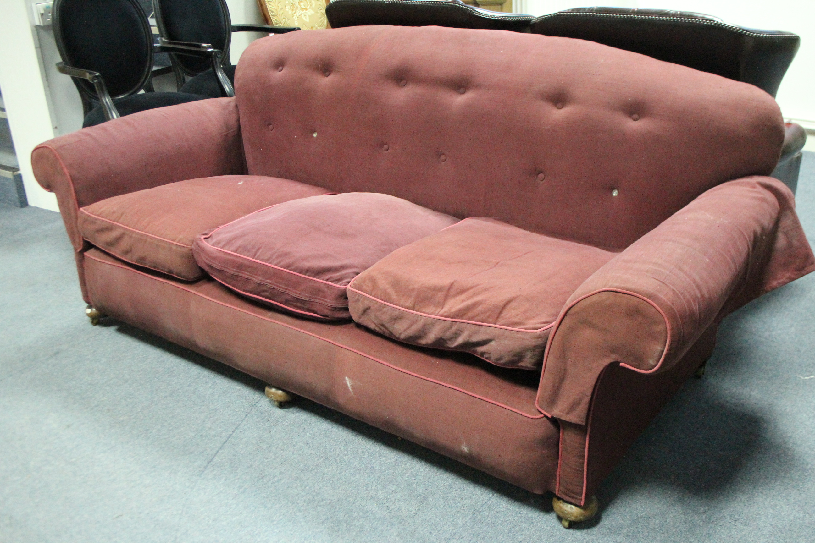 An early 20th century three-seat sofa upholstered burgundy fabric, with rounded buttoned back,