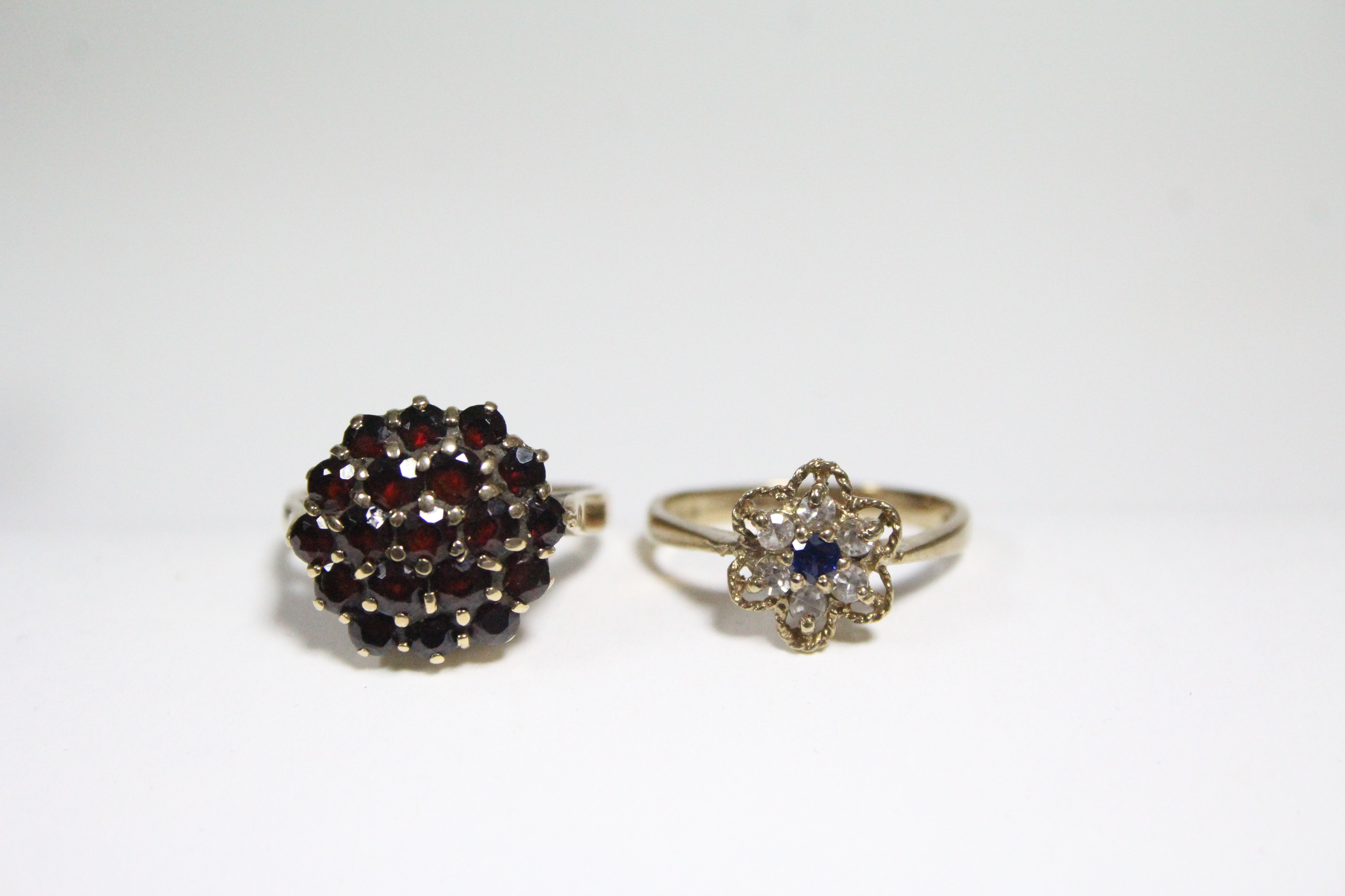 A 9ct. gold ring set cluster of blue & white sapphires; a gold ring set garnet cluster; & a pair
