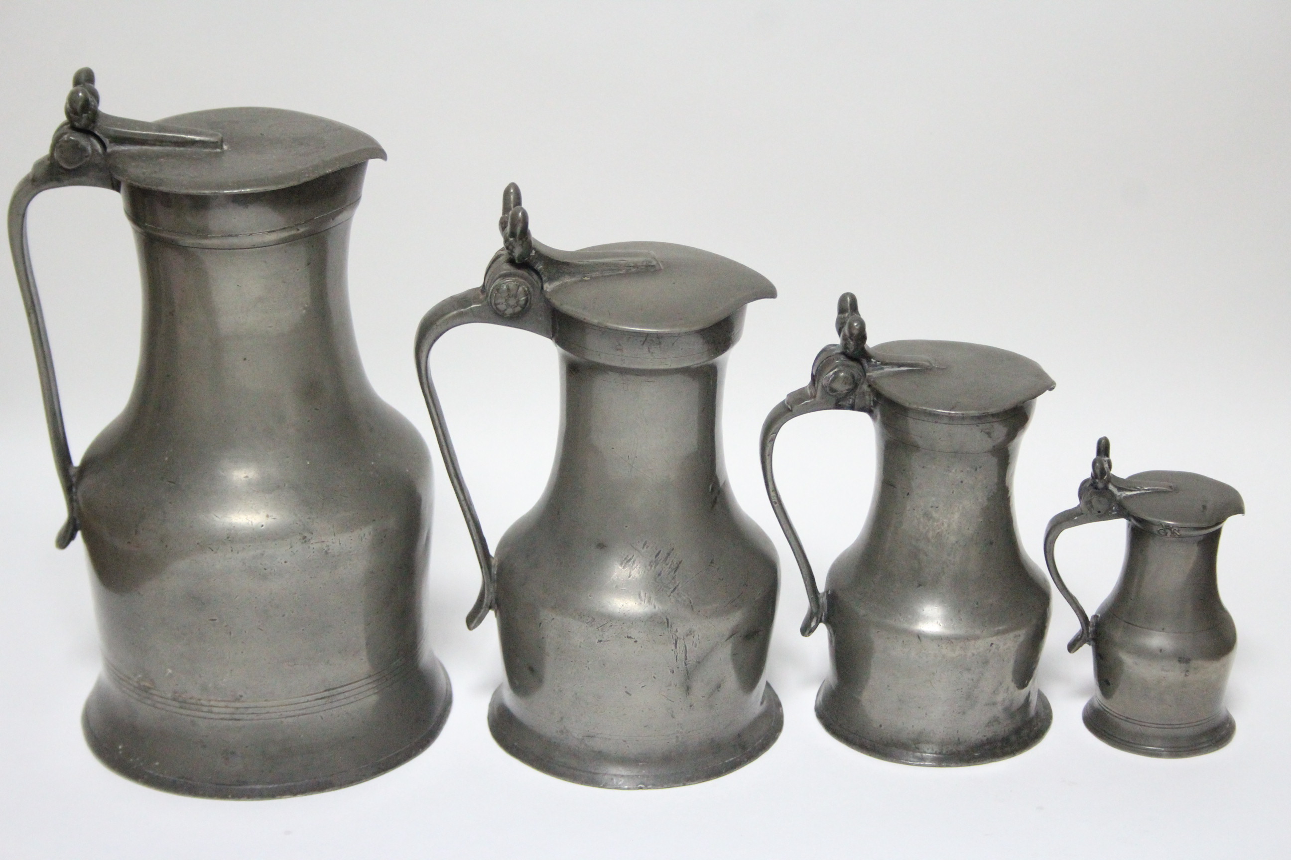 A matched set of four 19th century pewter graduated “Tappitt Hen” jugs, with double-acorn, thumb-
