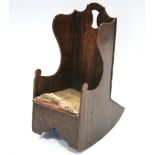 An 18th century oak child’s rocking chair, the wing-back with shaped pierced top, rounded arms, &