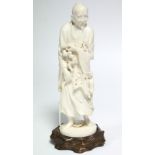 A late 19th century Japanese ivory okimono of a standing male scholar holding a scroll & a staff,