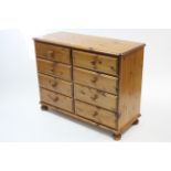 A pine low chest fitted two ranks of four long drawers, & on bun feet, 43” wide x 33” high.