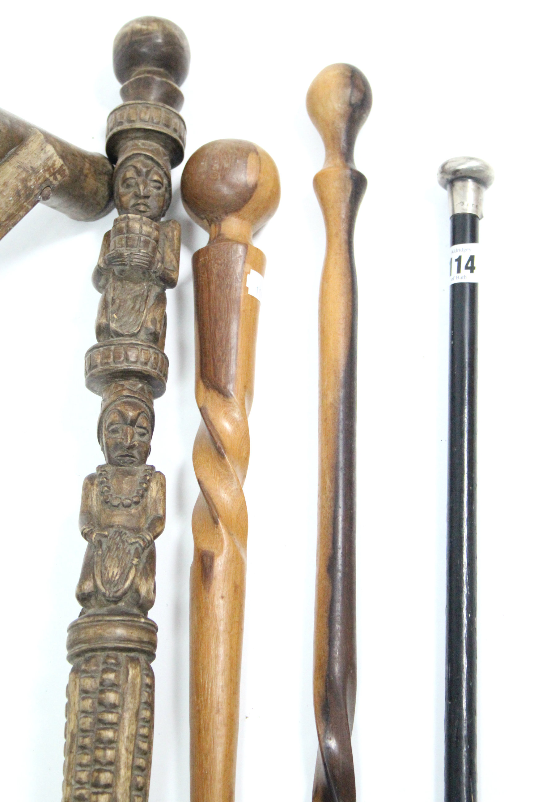 An ebonised gent’s walking cane with silver handle; together with three African wooden canes; a