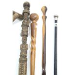 An ebonised gent’s walking cane with silver handle; together with three African wooden canes; a