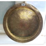 An eastern brass engraved circular tray, 16” diameter; a ditto pair of candlesticks; a ditto pair of