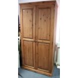 A pine wardrobe enclosed by pair of fielded panel doors, & on shaped plinth base, 39” wide x 79”
