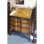 A reproduction burr-walnut bureau with fitted interior enclosed by fall-front above three long