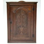 A late 18th century oak corner cupboard, the fielded panel door carved with vine-leaf decoration