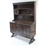 A reproduction oak dresser the upper part fitted three open shelves & with small cupboard to