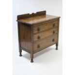 A 1930’s oak chest fitted three long graduated drawers with brass drop handles, & on bun feet, 36”