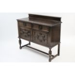 A 1930’s Jacobean-style oak small sideboard fitted two frieze drawers above cupboard enclosed by