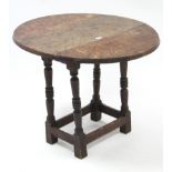 An oak circular drop-leaf occasional table on turned legs with plain stretchers, 27” diameter.