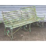 A late 19th/early 20th century green painted teak & iron garden bench on three scroll supports (