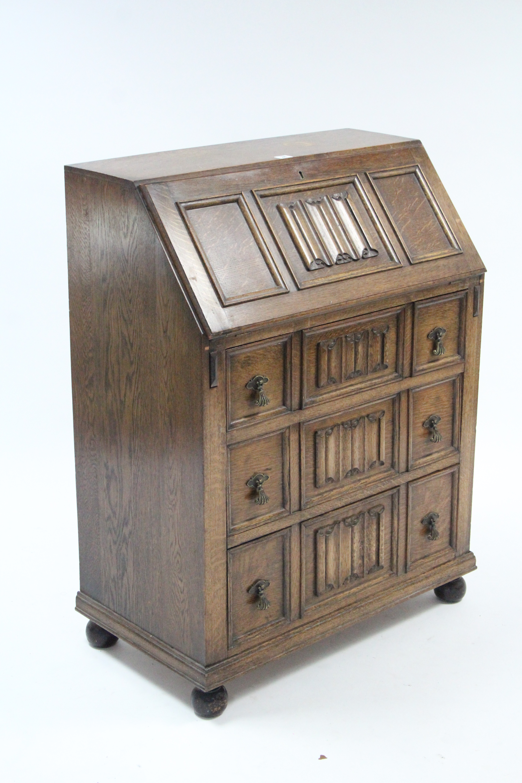 An early 20th century oak bureau with fitted interior enclosed by fall-front above three long