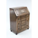 An early 20th century oak bureau with fitted interior enclosed by fall-front above three long