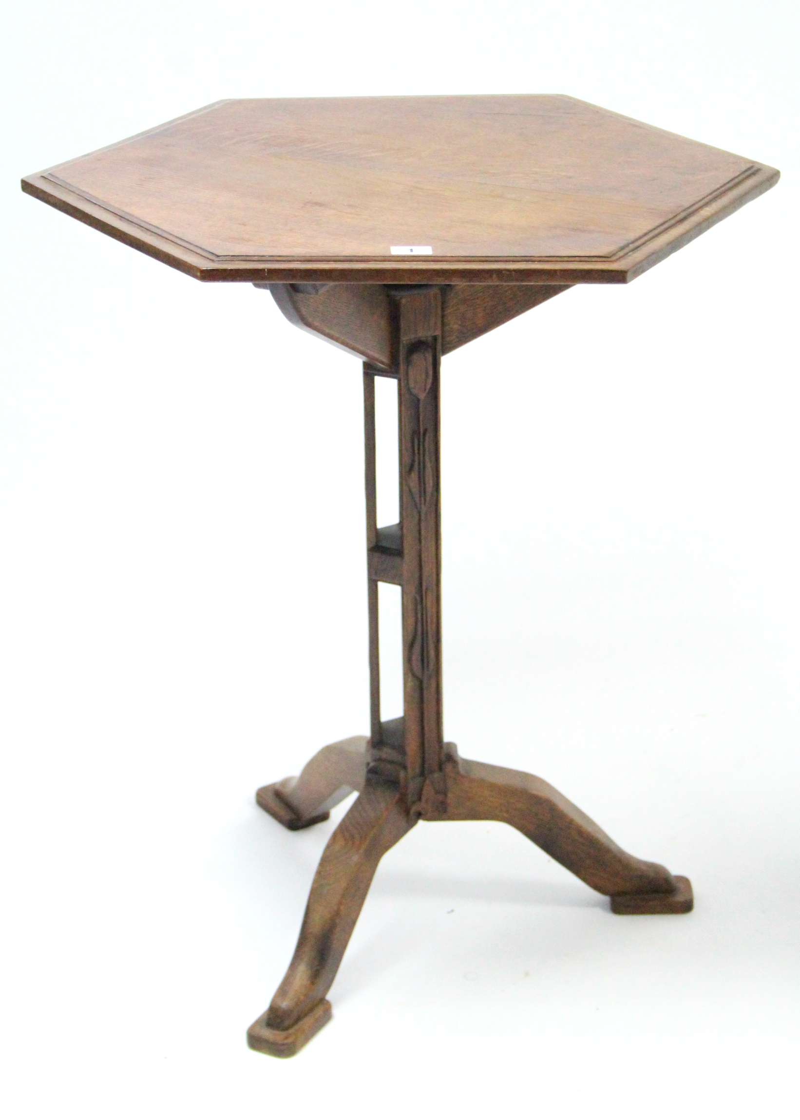 An arts & crafts oak tripod table with moulded edge to the six-sided top, & on pierced centre column